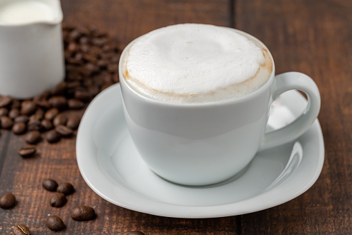 Cappuccino coffee in a white porcelain cup on a wooden table