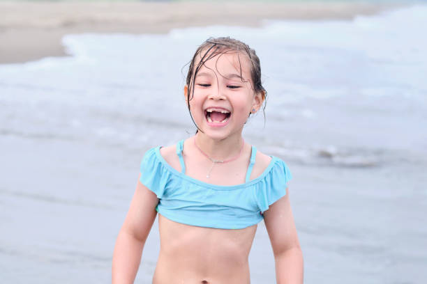 little happy girl running in swimsuit on the beach, on the sand, by the sea, portrait