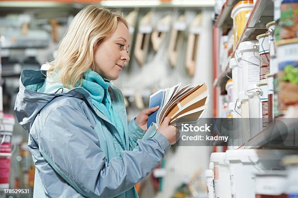 Photo libre de droit de Femme En Sélectionnant Peinture Au Magasin banque d'images et plus d'images libres de droit de Faire les courses - Faire les courses, Quincaillerie, Femmes