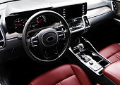 Modern car Interior. Steering wheel, shift lever and dashboard. Detail of modern car interior. Automatic gear stick. Part of red leather seats with stitching in expensive car