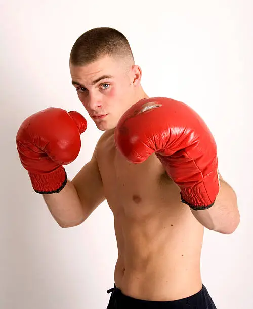 Young man with boxing gloves on and standing in defensive position