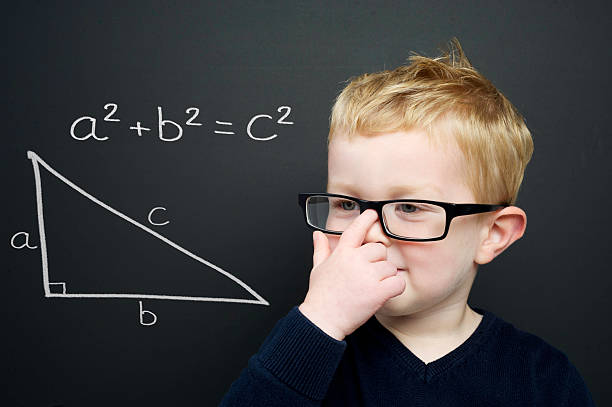 Smart young boy stood infront of a blackboard Smart young boy wearing a navy blue jumper and glasses stood infront of a blackboard with the Pythagoras rule explained drawn in chalk pythagoras stock pictures, royalty-free photos & images