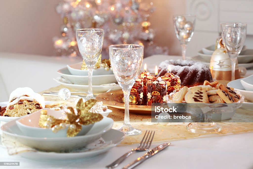 A decorated Christmas table for dinner Decorated Christmas table with tree in background Christmas Stock Photo