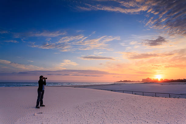man takes a photograph of sunrise stock photo