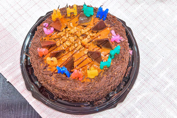 Birthday chocolate cake with extinguished candles on the table.