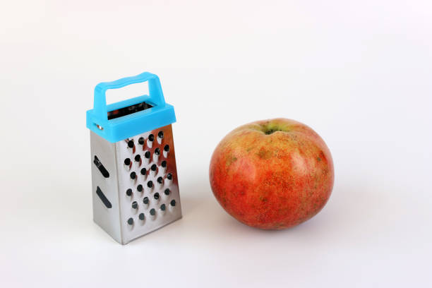 Hand held miniature grater and apple on a white background.
