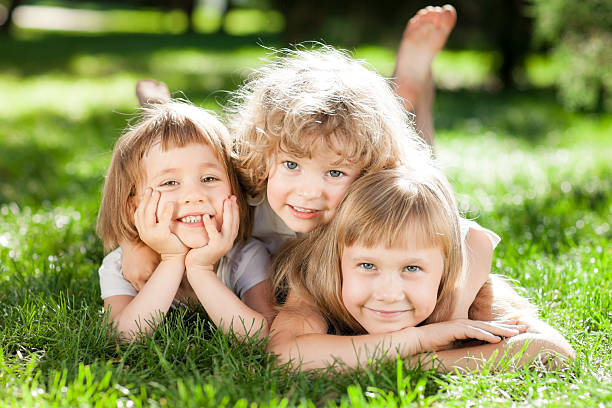 istock Three girls lie on a green grass 178534707