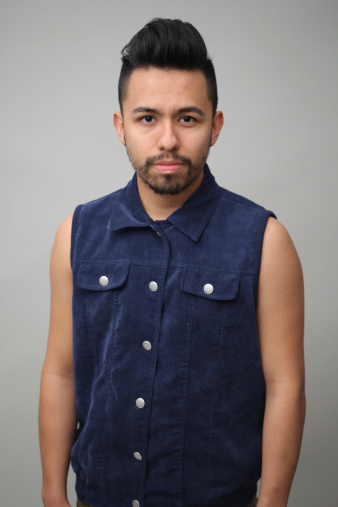 Young handsome male adult staring at the camera in the studio. Hes wearing a corduroy blue vest
