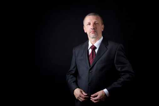 Serious mature businessman looking at camera. Black background