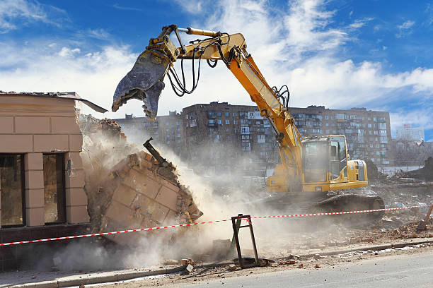 Building demolition machine pulls down a wall on a sunny day Bulldozer crushing the building at construction site bulldozer photos stock pictures, royalty-free photos & images