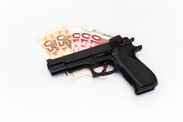An iron pistol lies on a white background with money.