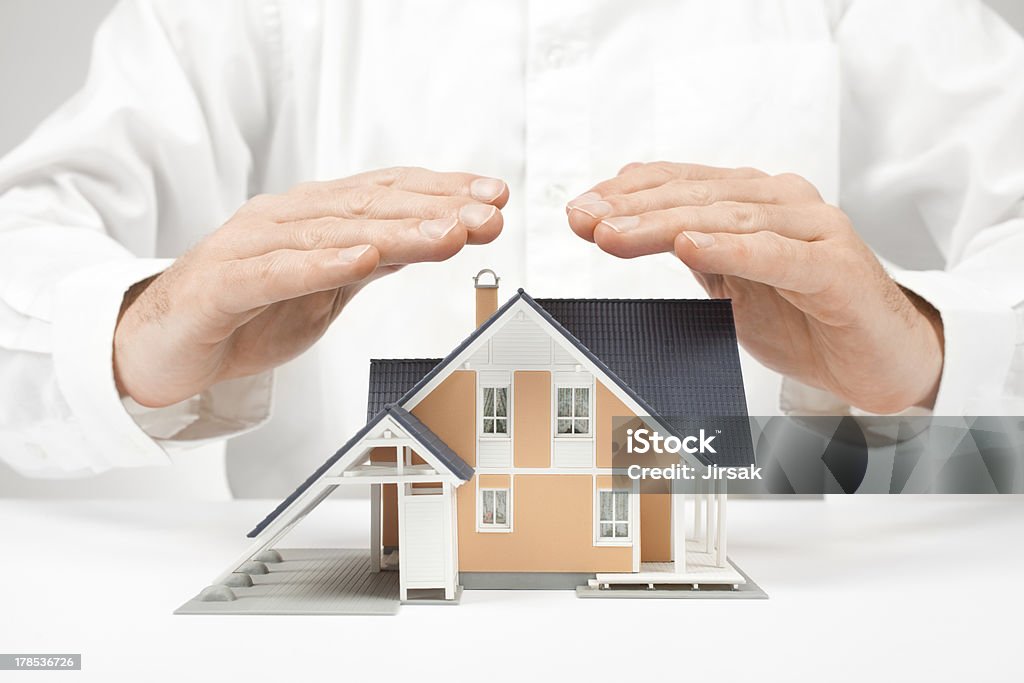 Protect house - insurance concept Property insurance concept - man protect model of the house. Adult Stock Photo