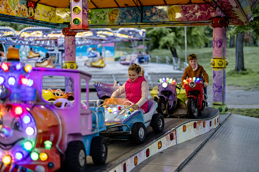 Giggles and laughter follow a child as they go round and round on motorized vehicles, infusing the amusement park with infectious joy and endless fun