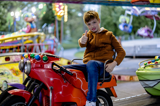 With each spin, a child dives deeper into a world of fun and excitement, riding on motorized vehicles and embracing the thrilling experience at the amusement park