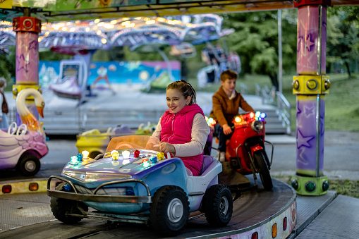 Heart-pounding thrills await as a child embarks on a spiraling adventure, riding on motorized rides and discovering the exhilaration of motion at the amusement park
