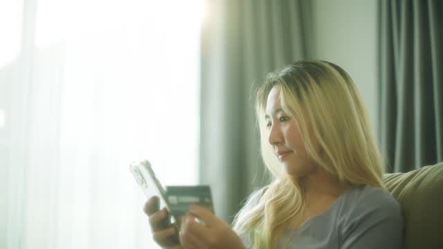 Young asian woman online shopping with credit card and smartphone.