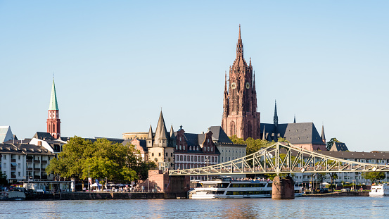 Frankfurt am Main, Germany - August 18, 2023: The bell tower of Frankfurt Cathedral overlooks the steeple of Alte Nikolaikirche, the Saalhof with the Rententurm and the Eisernen Steg on the river Main