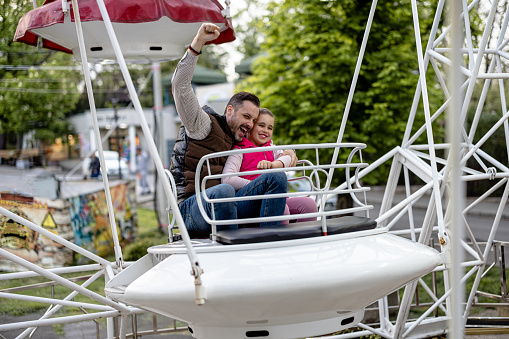 Amidst the whimsical carousel music, a father and his daughter experience pure bliss, finding happiness in each other's company on the merry-go-round