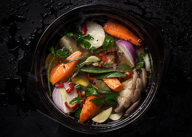 Uncooked Soupe de légumes en pot de céramique sur fond noir - Photo