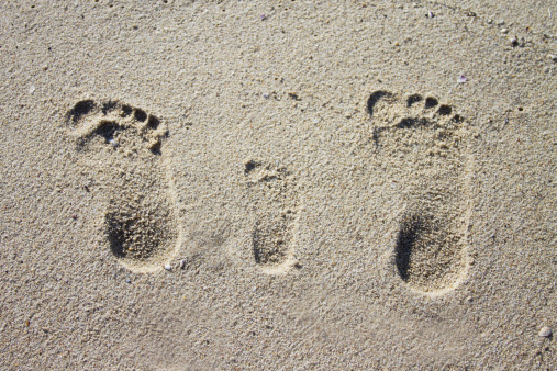 Stock photo showing close-up view of man's feet crossed at ankles on wooden table.