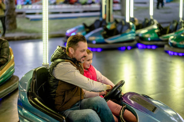 vater und tochter navigieren durch nervenkitzel auf den autoscootern des vergnügungsparks - the thrills stock-fotos und bilder