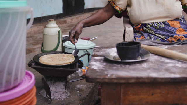 SLO MO of mature female cooking traditional food. Woman is sitting at table. She is outside house.