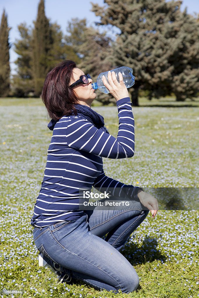Meados idade mulher relaxante e água potável na relva - Royalty-free 40-44 anos Foto de stock
