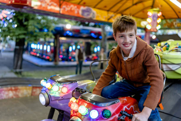 kind liebt den nervenkitzel motorisierter fahrgeschäfte im vergnügungspark - the thrills stock-fotos und bilder