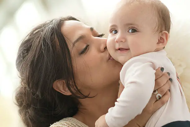 Mother holding and kissing baby girl