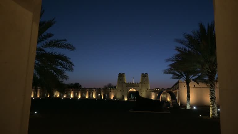 People walking pass  the Al Jahili Fort at night with illuminated light. Famous fort, Tourist destination in Al Ain, Abu Dhabi, UAE