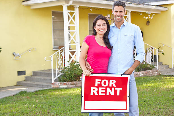 casal em pé pela para alugar sinal fora de casa - for rent sign house sign happiness imagens e fotografias de stock