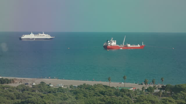 A Cruise Liner and a Cargo Tanker are moored not far from the shore. A view from above.