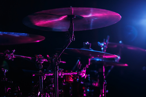 Professional drum set on rock concert in magenta and blue stage lights