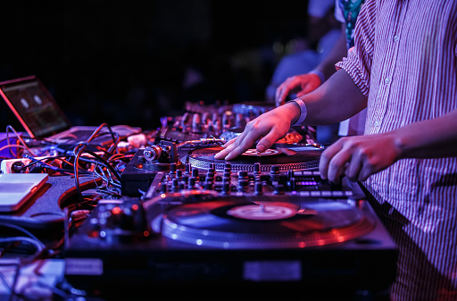 Hip hop DJ scratches vinyl records on turntables. Disk jockey mixing music set on concert