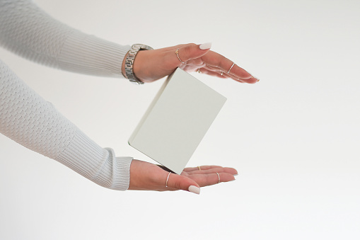 A elegant woman hand holds light blue box. Perfume present for her. Mock up.