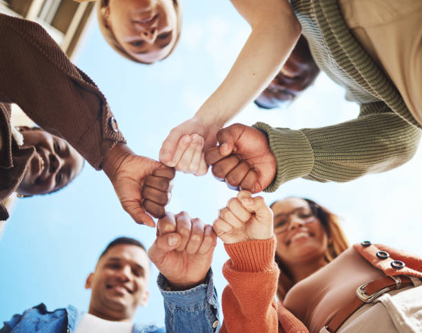 istock Group of friends, hands bump in huddle and group diversity, team building circle from below. Friendship, happiness and university students in fist bump, men and women smile together on college campus 1785432294
