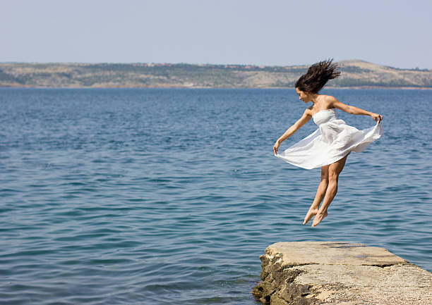 istock Beautiful young woman jumping on the pier 178543674