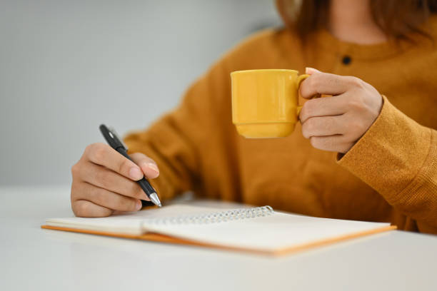 istock Young woman drinking hot coffee and writing notes in personal daily planner 1785437111