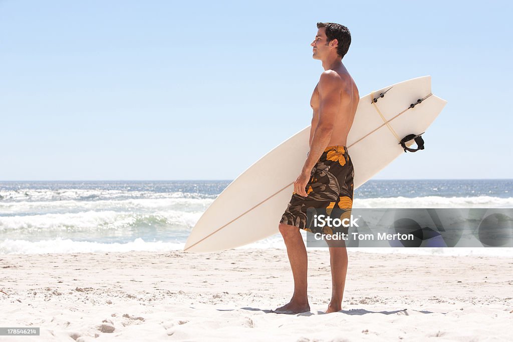 Hombre con tabla de surf en la playa - Foto de stock de 30-39 años libre de derechos