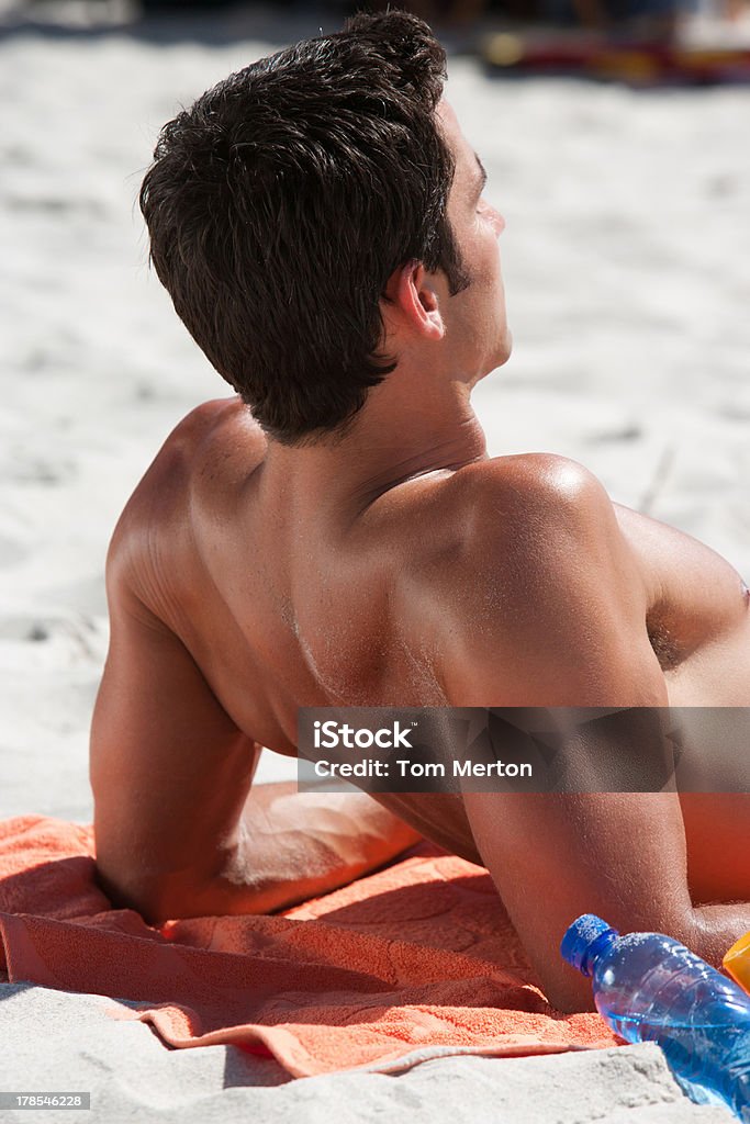 Hombre acostado en la playa de arena de toalla - Foto de stock de 30-39 años libre de derechos