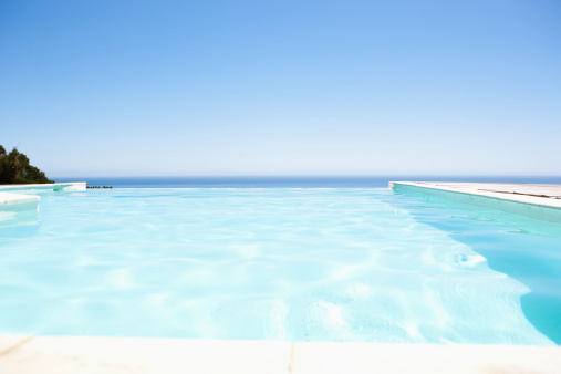 Stone podium stand in luxury blue pool water. Summer background of tropical design product placement display. Hotel resort poolside backdrop.