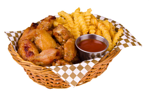 Chicken wings and french fries in a basket, isolated on white.