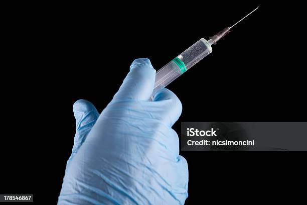 Doctor Holding A Syringe Stock Photo - Download Image Now - Accuracy, Black Background, Blue
