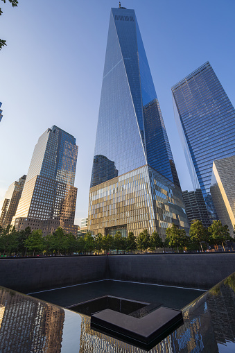 New York, NY, United States - July 25, 2023: Vertical shot of the North Tower pool of the 911 Memorial pools with the One World Trade Center in the background