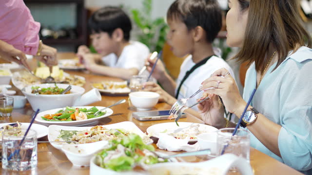 Asian family eats the many dishes on the table together for a delicious brunch.
