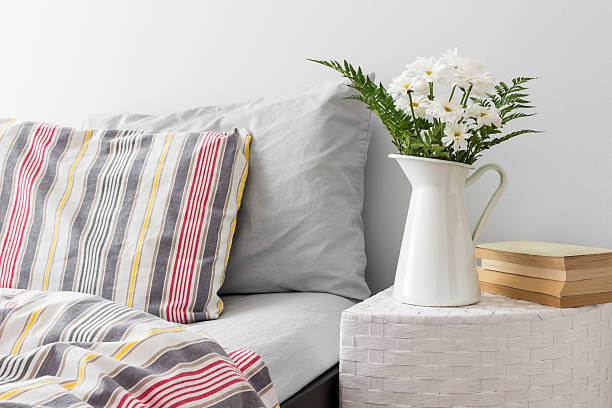 White flowers and books on a bedside table White flowers and books on a side table near a bed. Fresh design. red cushion covers stock pictures, royalty-free photos & images
