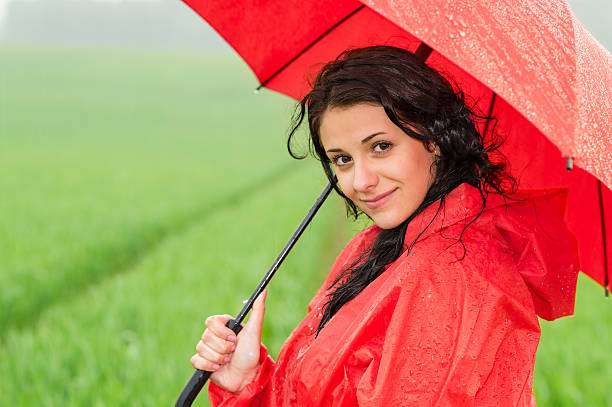 Smiling woman looking at camera during rainfall posing with umbrella