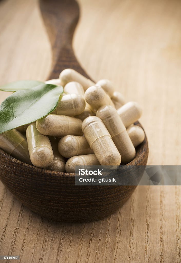 Alternative Medicine. Alternative medicine tablets on a wooden spoon, green leaf. Backgrounds Stock Photo