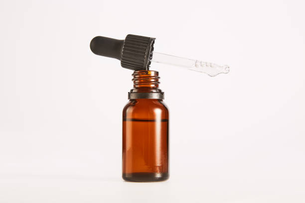 istock Black cap with pipette lies on open brown glass bottle. 1785515328