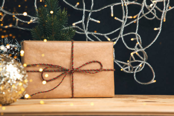 istock Background for greetings. Gift wrapping in brown paper on a wooden table on black background 1785522331